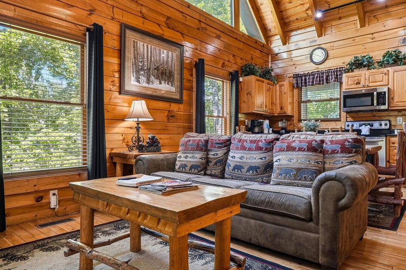 Step into your cozy mountain retreat where rustic charm meets comfort. Sunlight streams through tall windows, warming the open living space with its inviting wood accents and plush seating.