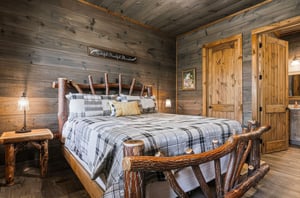 Sink into the handcrafted log bed, wrapped in soft plaid comfort under warm woodpaneled ceilings. Rustic touches and bedside lamps create a cozy, mountainstyle retreat.