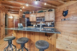 Step into your rustic mountain kitchen where granite counters meet warm wood beams, creating the perfect space for morning coffee and meal prep.