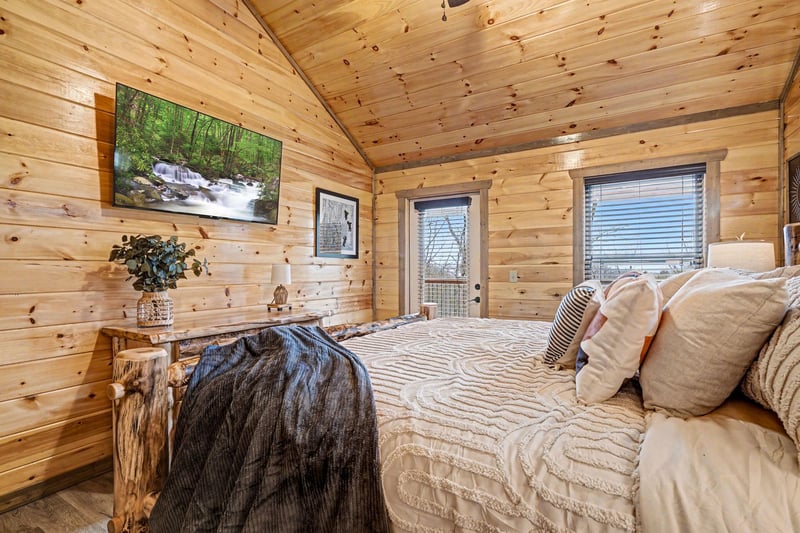 Drift off in your cozy cabin bedroom, surrounded by warm wood and soft linens under the rustic beamed ceiling.