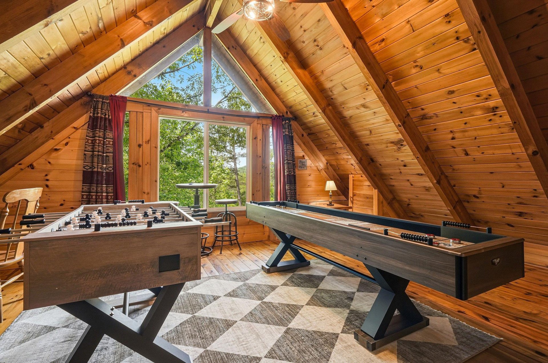 Your own mountain game room awaits under soaring timber ceilings, with foosball and shuffleboard ready for friendly competition as natural light streams through picture windows framing forest views.