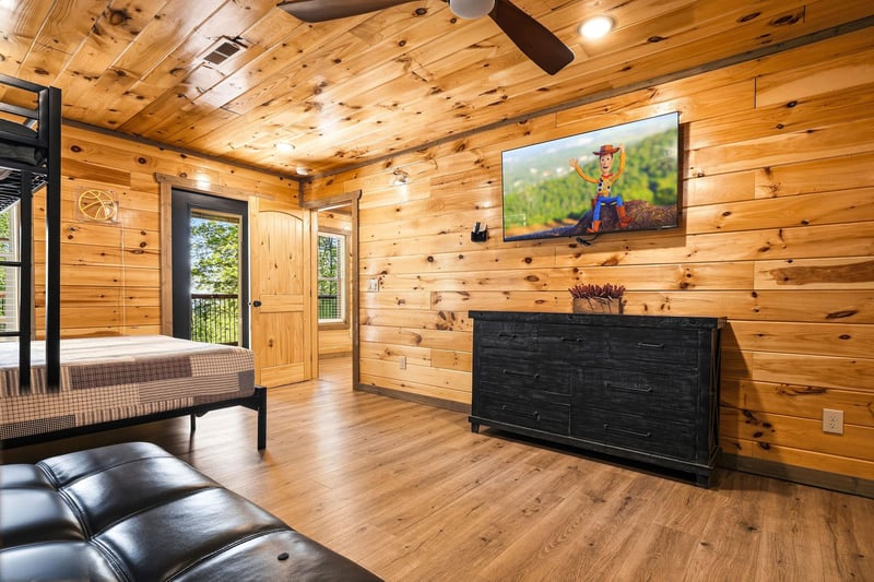 Your cozy cabin bedroom features warm wood walls, bunk beds, and a large TV for movie nights together.