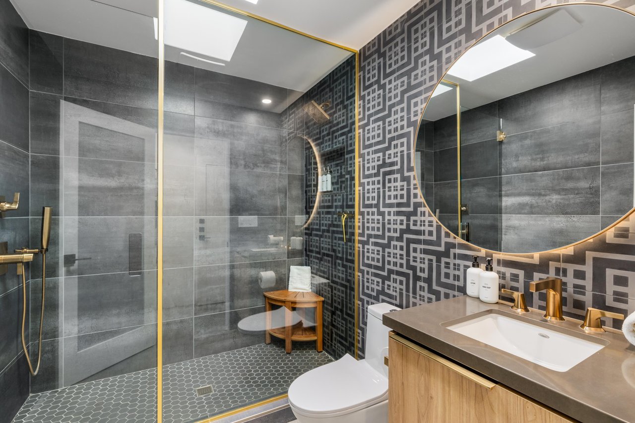 Step into your designer bathroom with gold fixtures, walkin shower, and stunning geometric tiles that create a spalike sanctuary.
