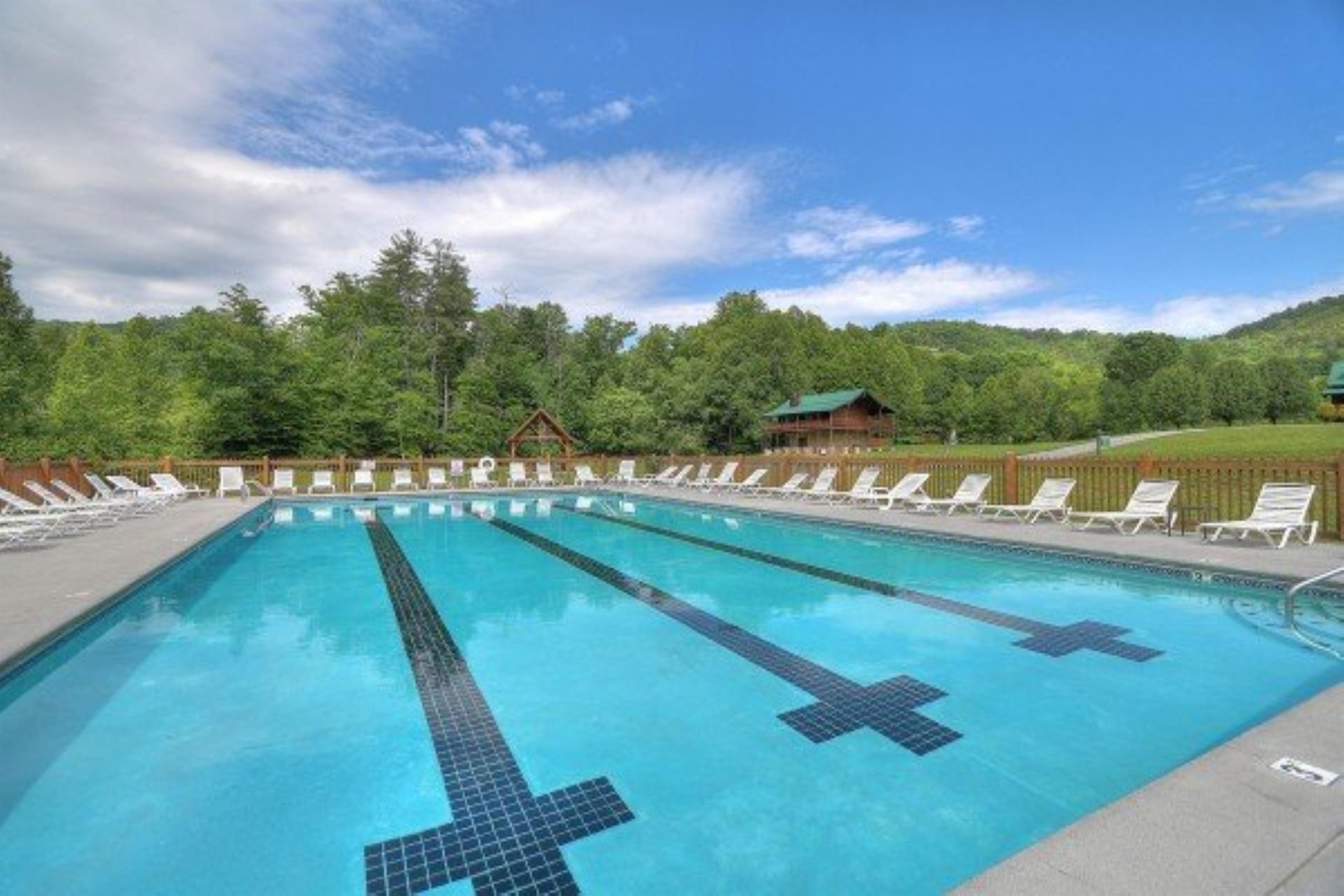 A spacious outdoor pool surrounded by lush mountain forest and abundant lounge seating offers a refreshing retreat with scenic views.