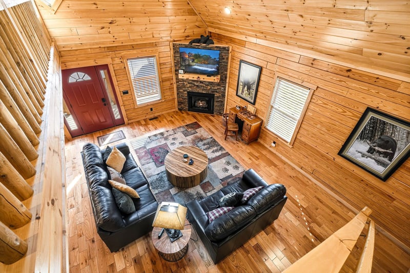 Relax in your cozy cabin living room with plush leather seating, crackling fireplace, and warm wood walls creating the perfect mountain retreat.