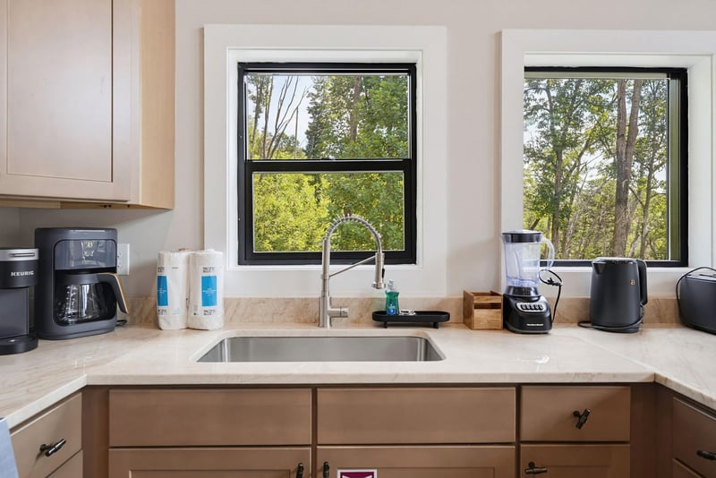 Your kitchen overlooks a peaceful, treelined backdrop that changes with the seasons. Natural light floods the space, while modern appliances make meal prep a breeze—coffee maker, blender, and electri