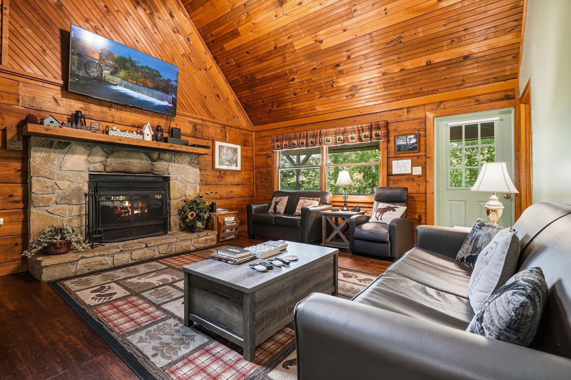 Sink into plush leather seating beside your crackling stone fireplace, where rustic wood walls create the perfect mountain retreat atmosphere.