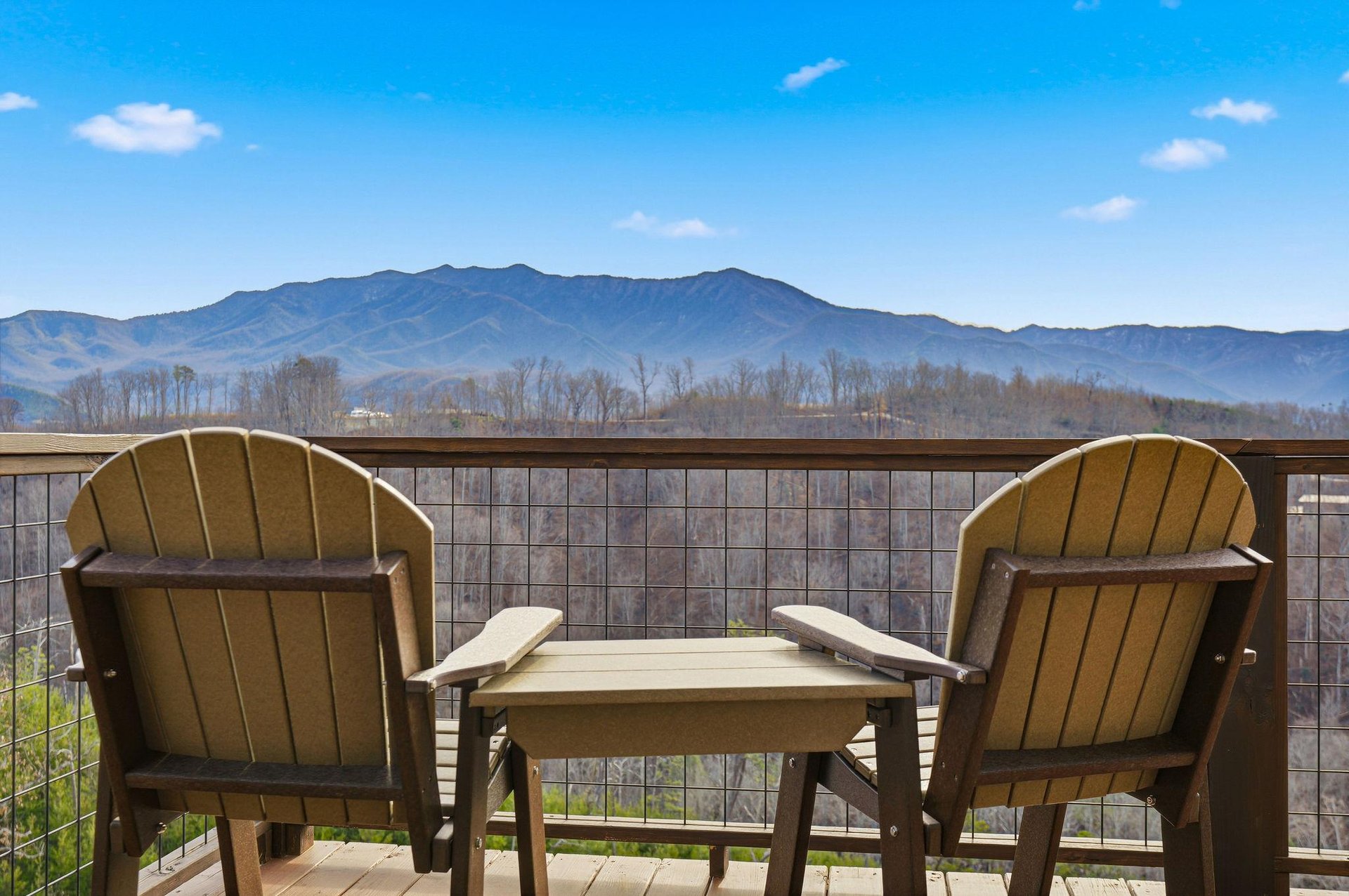 Private balcony seating overlooks stunning mountain ranges under brilliant blue skies.