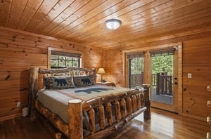 Wake up surrounded by warm wood walls in your cozy rustic bedroom, where bearthemed bedding meets handcrafted log furniture and private balcony access.