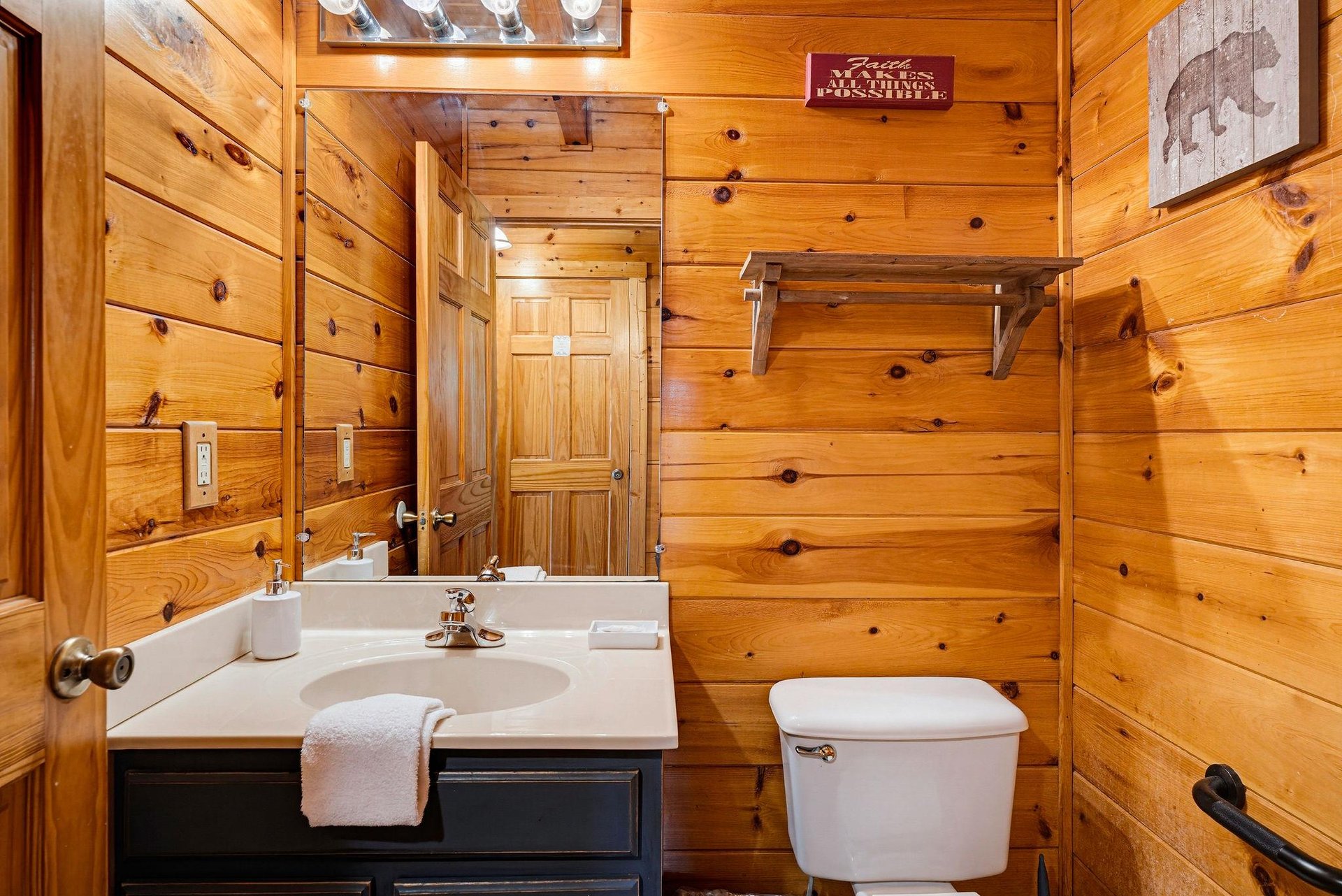 Relax in this cozy cabinstyle bathroom, where warm wood paneling and thoughtful fixtures create a rustic yet polished retreat after your mountain adventures.