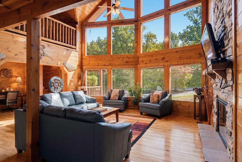 Step into this stunning cabin where soaring cathedral ceilings and towering windows flood your space with natural light. Sink into plush seating by the stone fireplace and gaze through walls of glass 