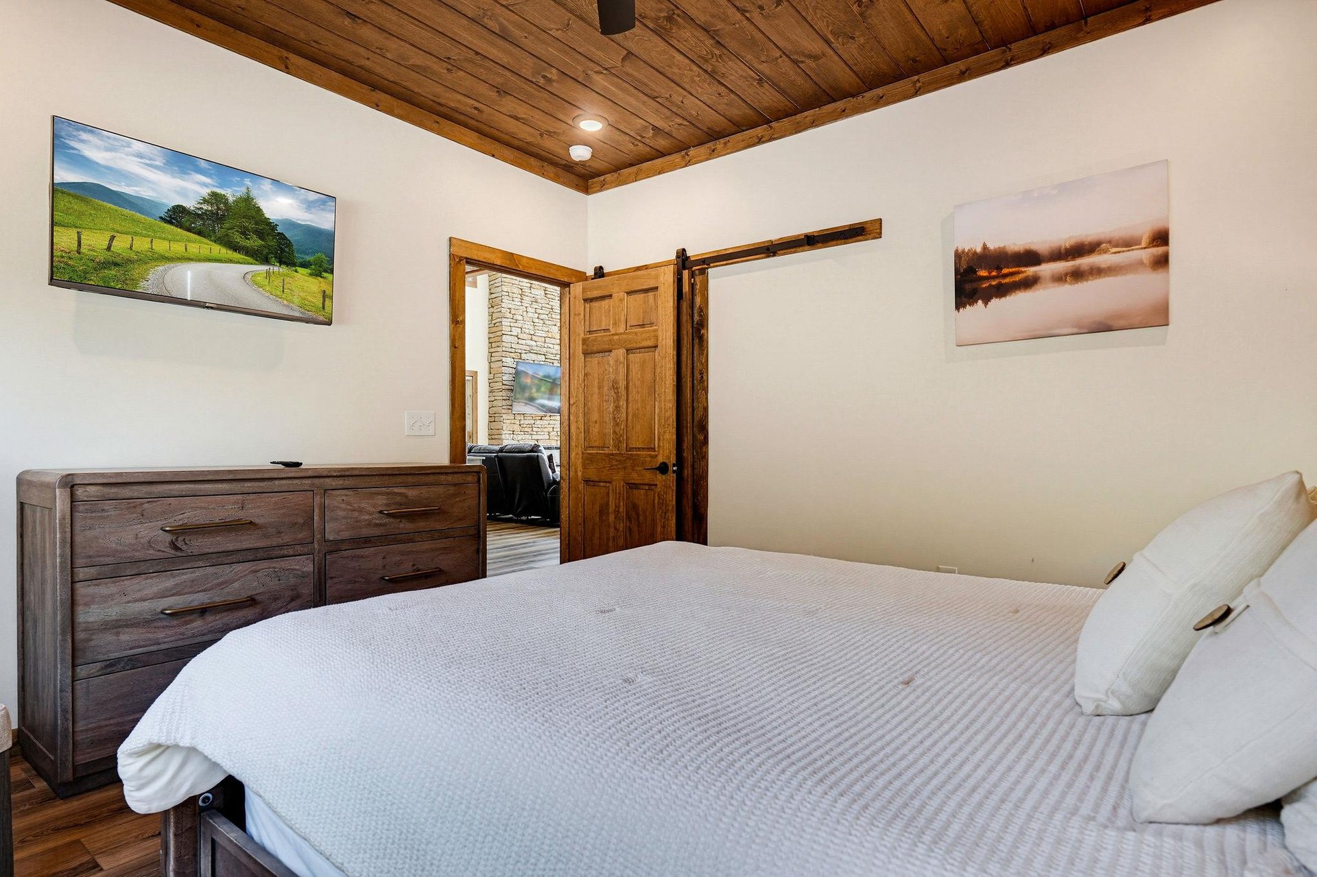Unwind in your peaceful retreat with rustic wood details, a cozy bed dressed in soft linens, and a charming barn door that adds character to your space.