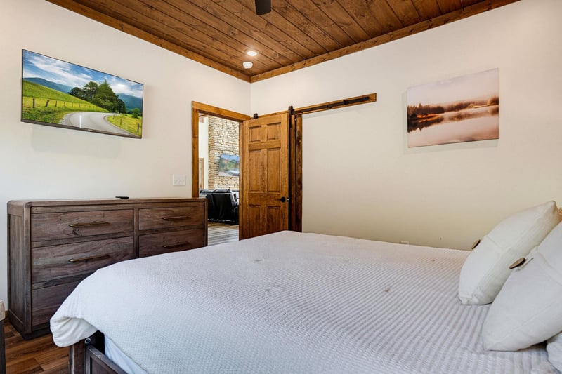 Unwind in your peaceful retreat with rustic wood details, a cozy bed dressed in soft linens, and a charming barn door that adds character to your space.