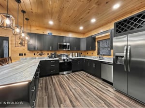 Cook delicious meals in this modern kitchen featuring stainless steel appliances, granite counters, and warm wood ceilings that create a cozy cabin atmosphere.