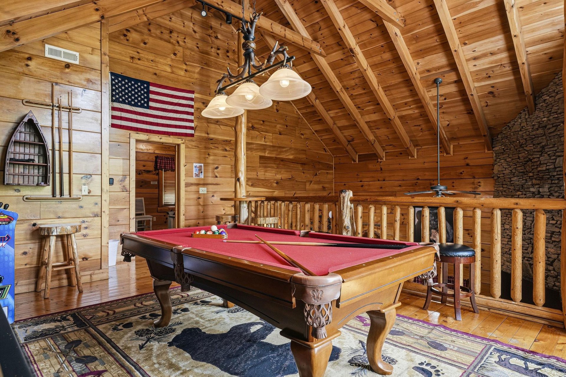 Challenge your travel companions to a friendly pool game in this inviting game loft, where rustic wood beams and a stone fireplace create the perfect mountain escape atmosphere.
