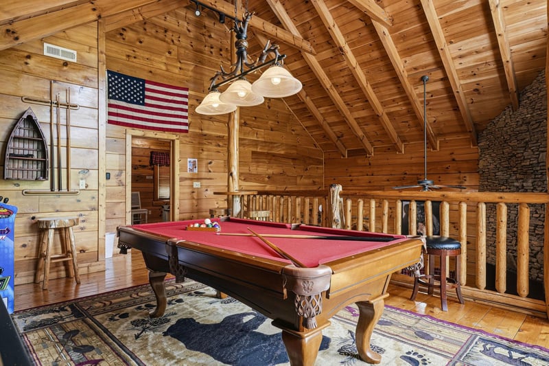 Challenge your travel companions to a friendly pool game in this inviting game loft, where rustic wood beams and a stone fireplace create the perfect mountain escape atmosphere.