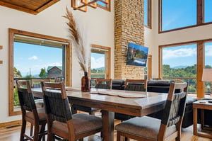 This bright, open dining space invites you to gather with loved ones while soaking in mountain views through floortoceiling windows. Natural wood accents and vaulted ceilings create a warm, welcomin