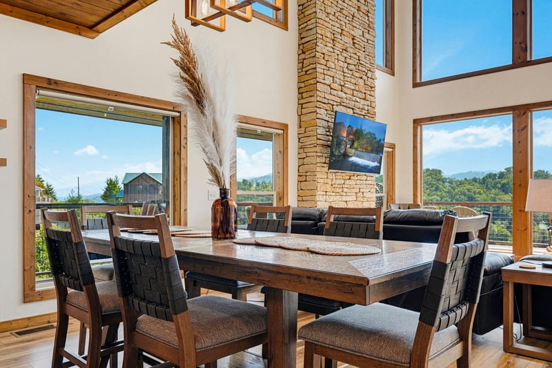 This bright, open dining space invites you to gather with loved ones while soaking in mountain views through floortoceiling windows. Natural wood accents and vaulted ceilings create a warm, welcomin