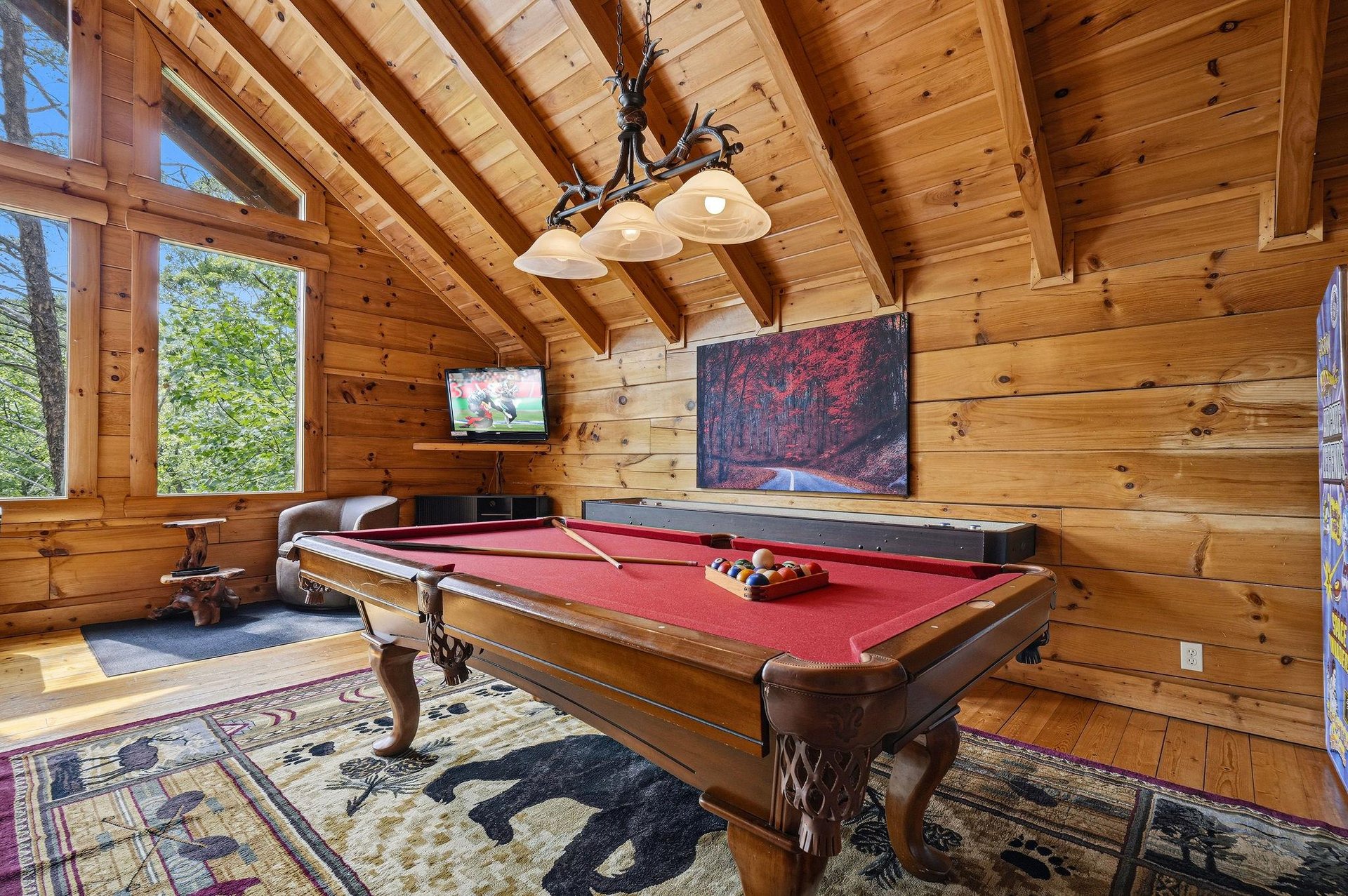 Challenge your friends to a friendly game of pool in this cozy game room, surrounded by warm wood and natural light streaming through tall windows.