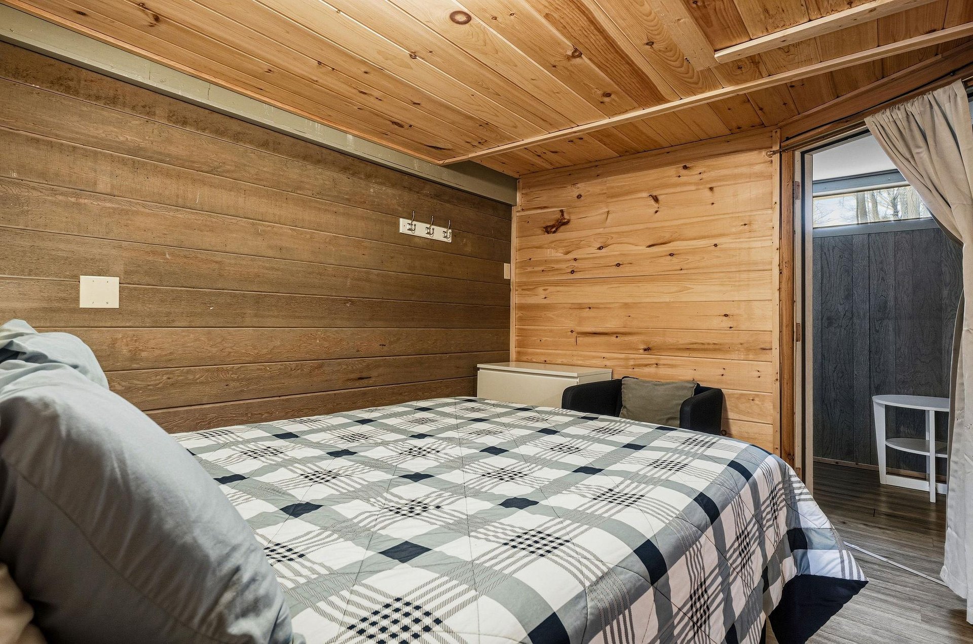 Unwind in your cozy woodlined bedroom where natural pine walls create a warm cabin atmosphere for peaceful nights.