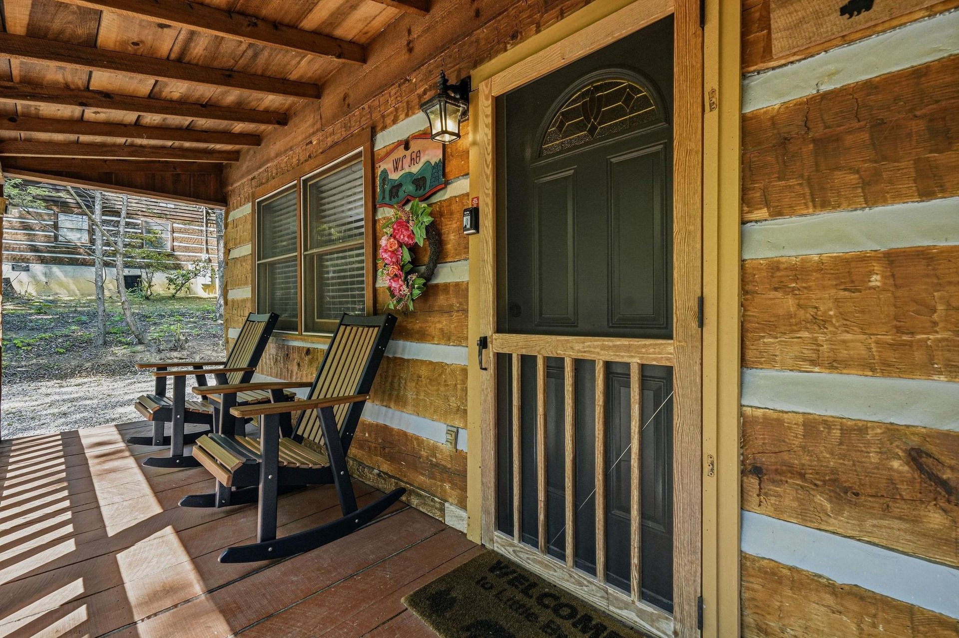 The charming log cabin façade showcases a welcoming covered porch where you can unwind in classic rocking chairs after a day of exploring.