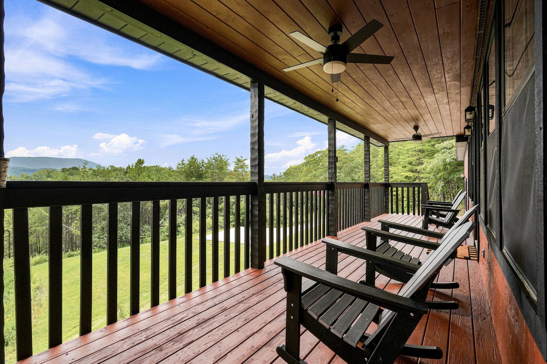 Step onto your private covered balcony and settle into relaxed seating as you take in sweeping views of lush green valleys and mountains. A peaceful escape awaits under a warm wood ceiling with coolin
