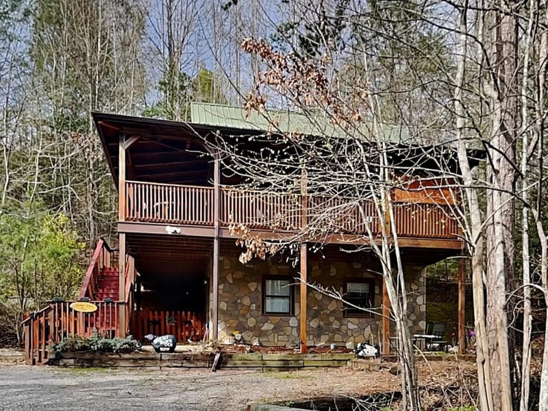 A cozy stoneandwood cabin in the mountains awaits, featuring a spacious upperlevel deck perfect for morning coffee and a welcoming covered porch downstairs, all tucked peacefully into the surroundi