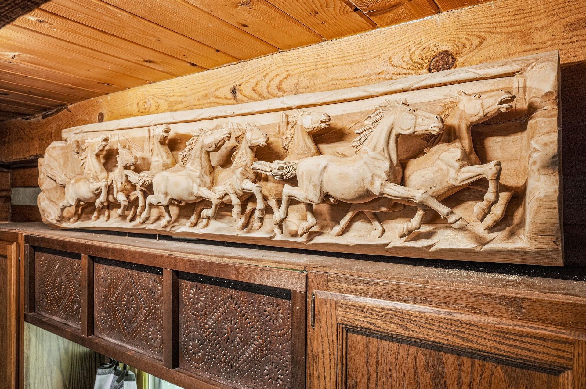 Admire this stunning handcarved relief of wild horses in midgallop, bringing timeless artistry and rustic charm to your mountain retreat.