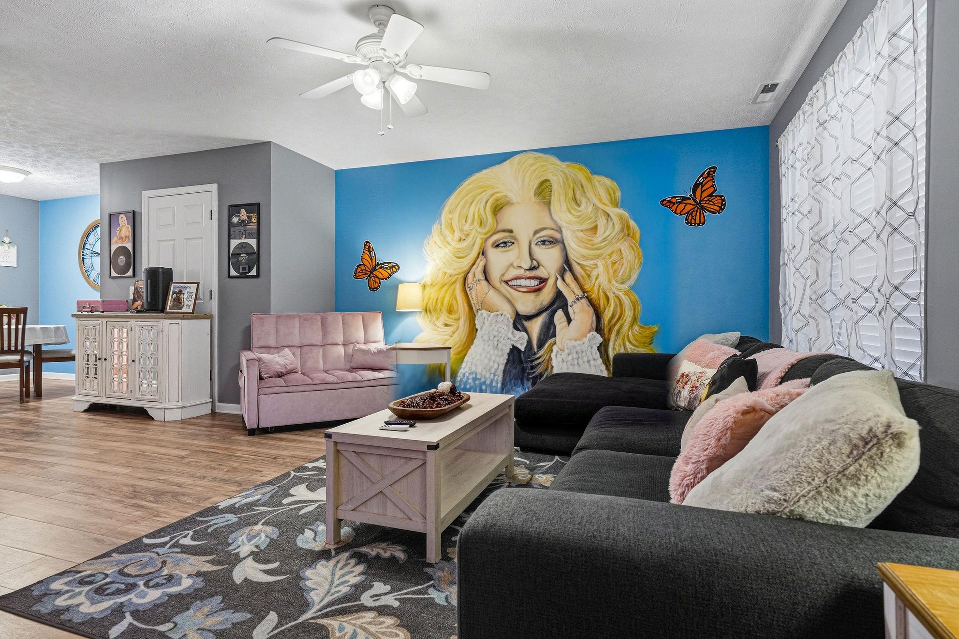 Step into a vibrant living space with cozy seating, warm wood accents, and a stunning statement mural that sets a joyful, welcoming tone for your stay.