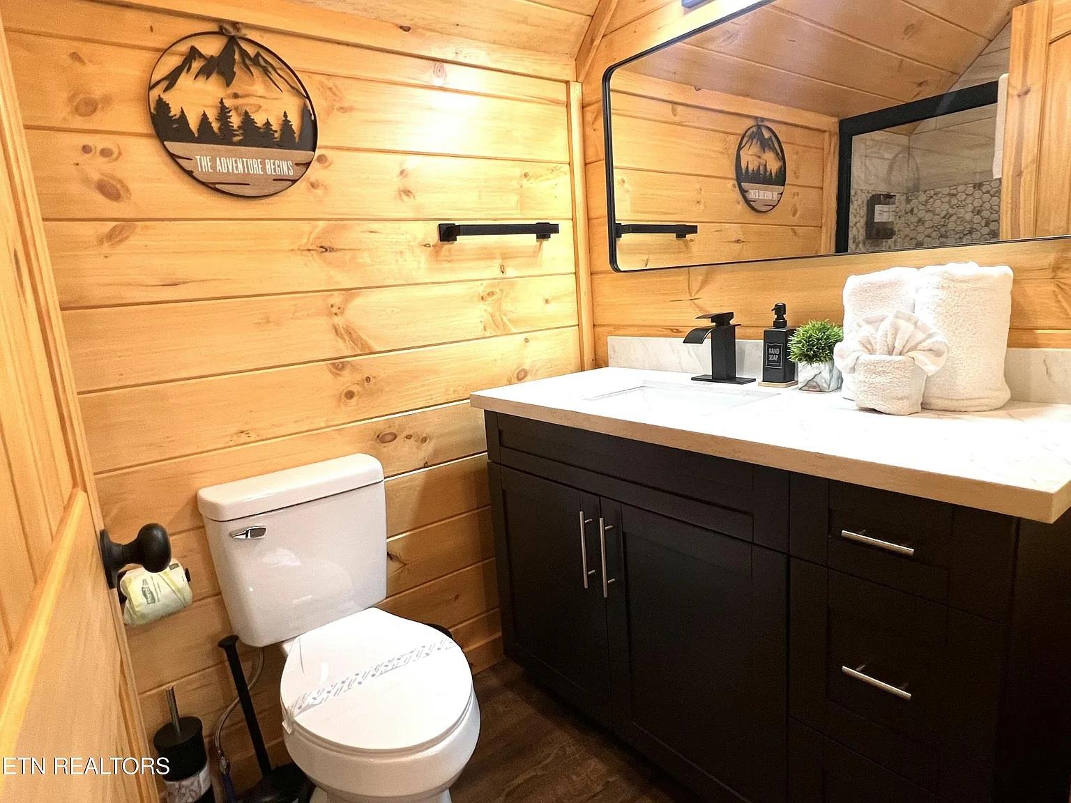 Unwind in your rusticmodern bathroom featuring warm wood walls, stylish dark vanity, and adventurethemed decor that makes your mountain retreat feel like home.