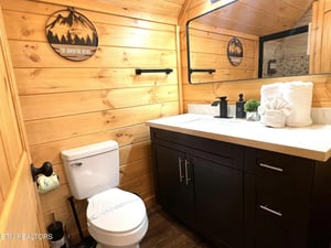 Unwind in your rusticmodern bathroom featuring warm wood walls, stylish dark vanity, and adventurethemed decor that makes your mountain retreat feel like home.