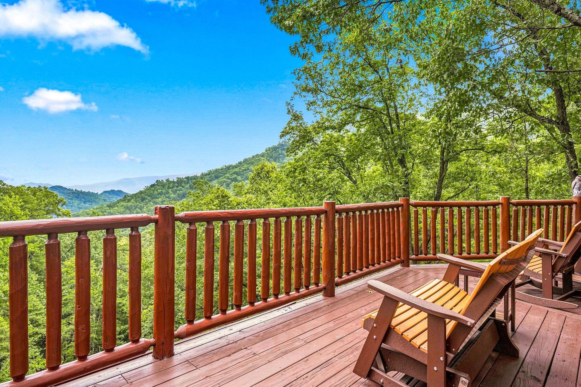 A spacious wooden deck overlooking a stunning mountain vista, perfect for your morning coffee or evening relaxation. Settle into the Adirondack chairs and soak in the peaceful, forested scenery stretc
