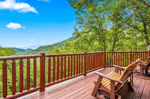 A spacious wooden deck overlooking a stunning mountain vista, perfect for your morning coffee or evening relaxation. Settle into the Adirondack chairs and soak in the peaceful, forested scenery stretc