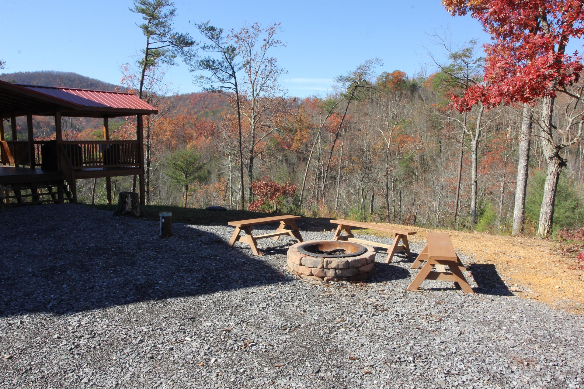 Looking at the fire pit and covered deck in the fall Four Seasons Lodge, a 3bedroom cabin rental located in Pigeon Forge