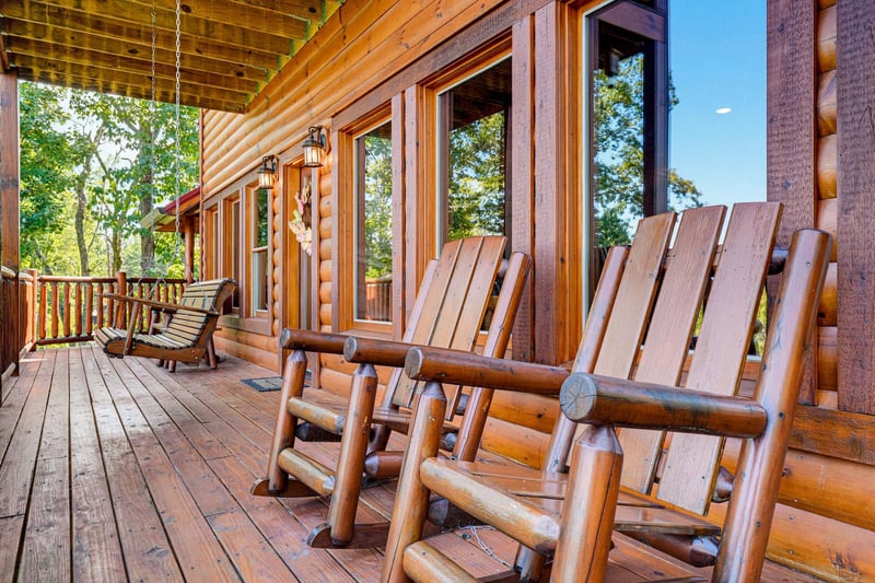 Spacious covered deck with handcrafted log rockers, a porch swing, and forest views—your perfect spot to unwind and breathe in the mountain air.