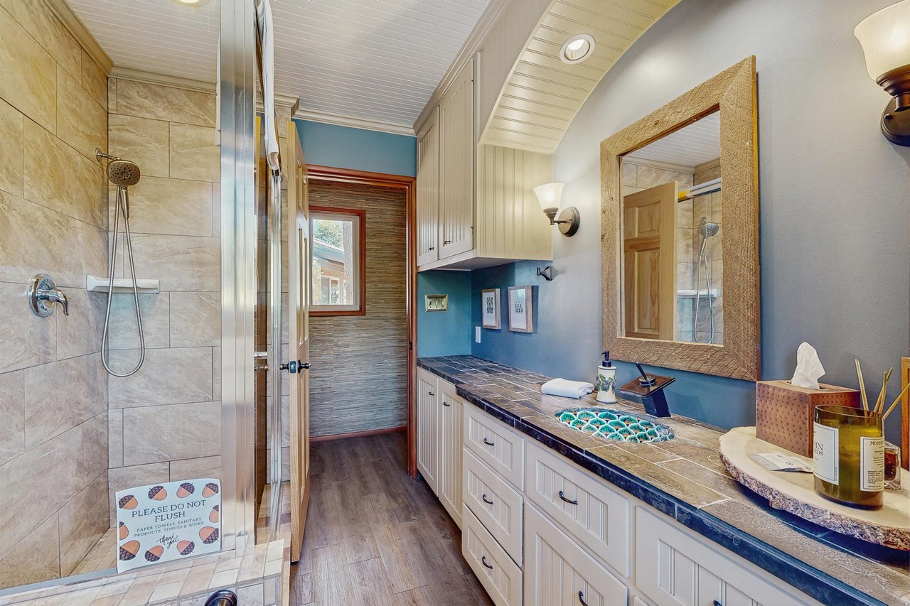 Full bathroom with walk in shower, detachable shower head, toilet, sink and plenty of vanity space.