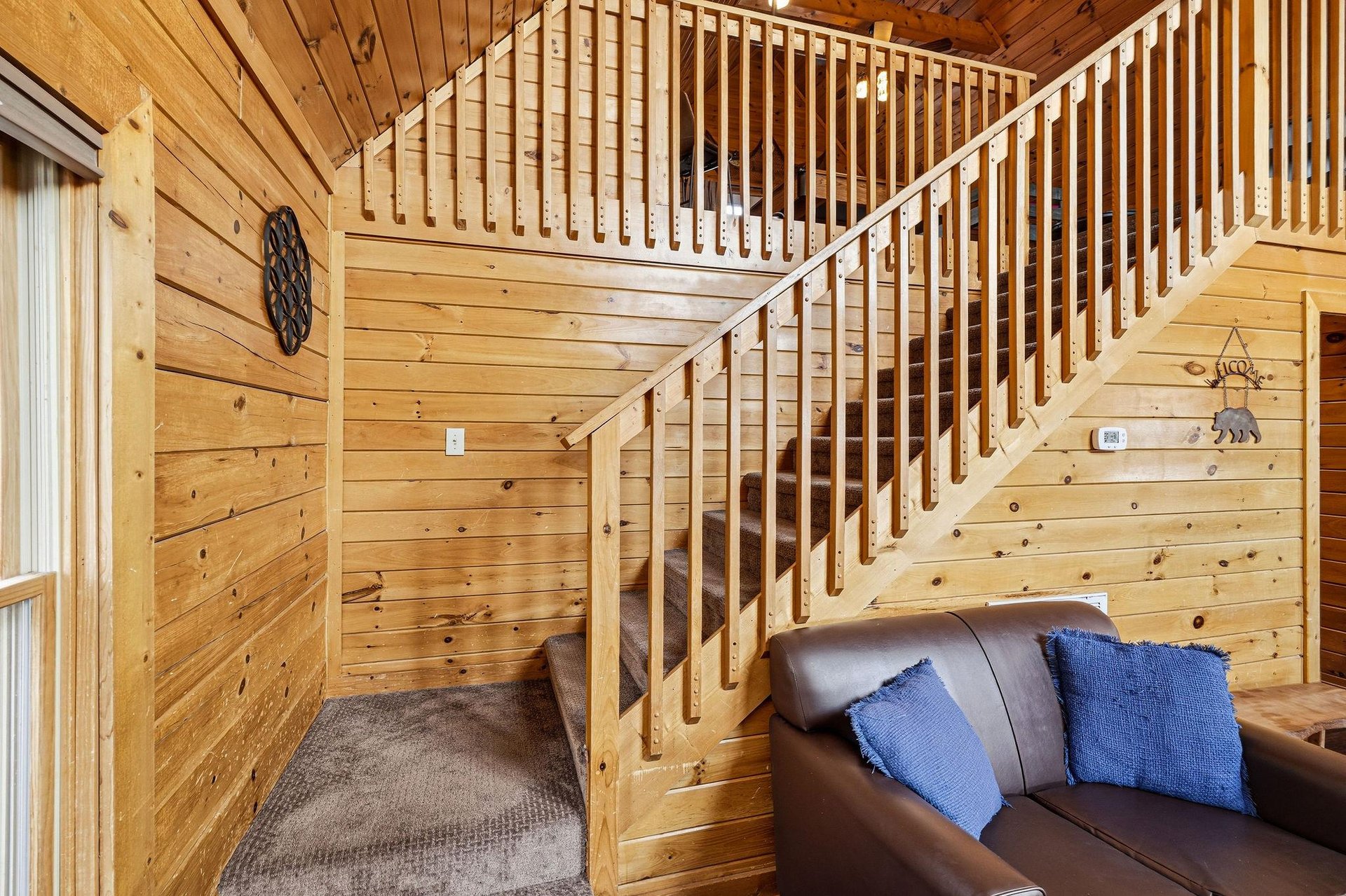 Your cozy cabin retreat features rich wood walls and rustic charm, with a comfortable leather sofa perfect for unwinding.