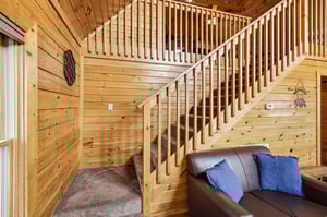 Your cozy cabin retreat features rich wood walls and rustic charm, with a comfortable leather sofa perfect for unwinding.