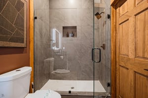 Your private bathroom features sleek marblelook tile, a modern glassenclosed shower, and warm wood accents that blend comfort with contemporary design.