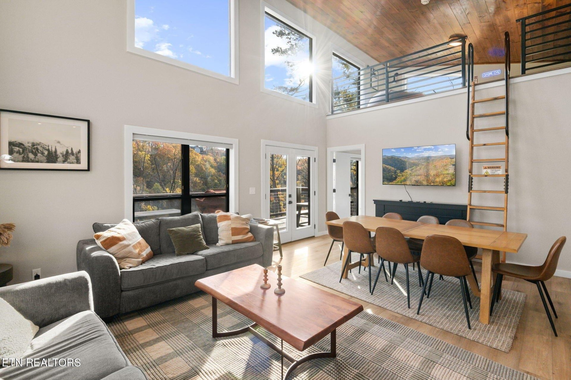 Step into your bright and airy retreat with soaring ceilings, warm wood accents, and large windows framing stunning autumn mountain views. Relax on plush sofas or gather around the spacious dining tab