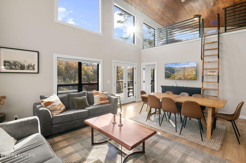 Step into your bright and airy retreat with soaring ceilings, warm wood accents, and large windows framing stunning autumn mountain views. Relax on plush sofas or gather around the spacious dining tab