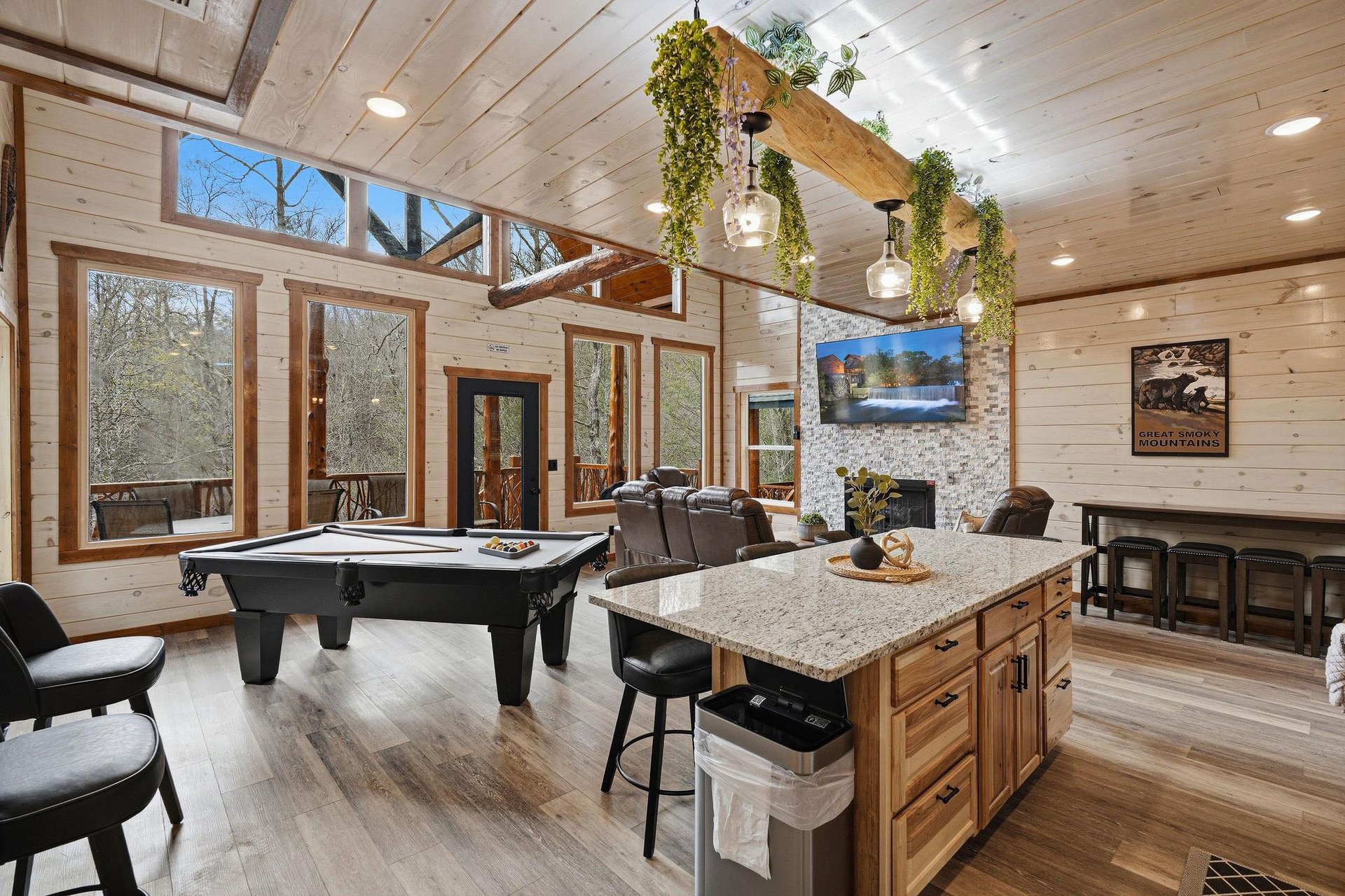 Unwind in your spacious game room with pool table, cozy fireplace, and stunning forest views through floortoceiling windows.