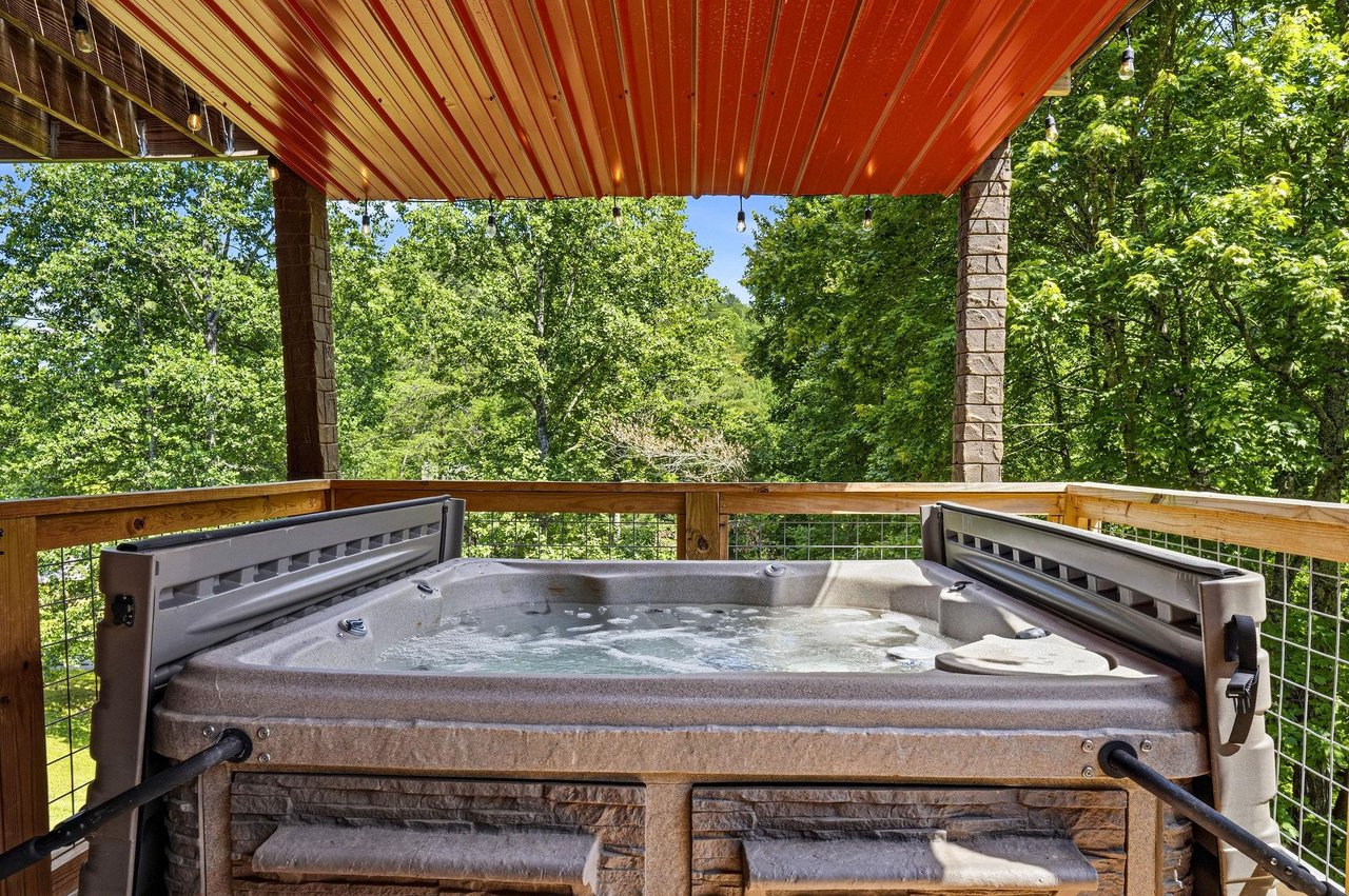 Sink into the bubbling hot tub while lush treetops frame your view, creating the perfect private retreat to unwind under a sheltering canopy.