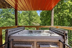 Sink into the bubbling hot tub while lush treetops frame your view, creating the perfect private retreat to unwind under a sheltering canopy.