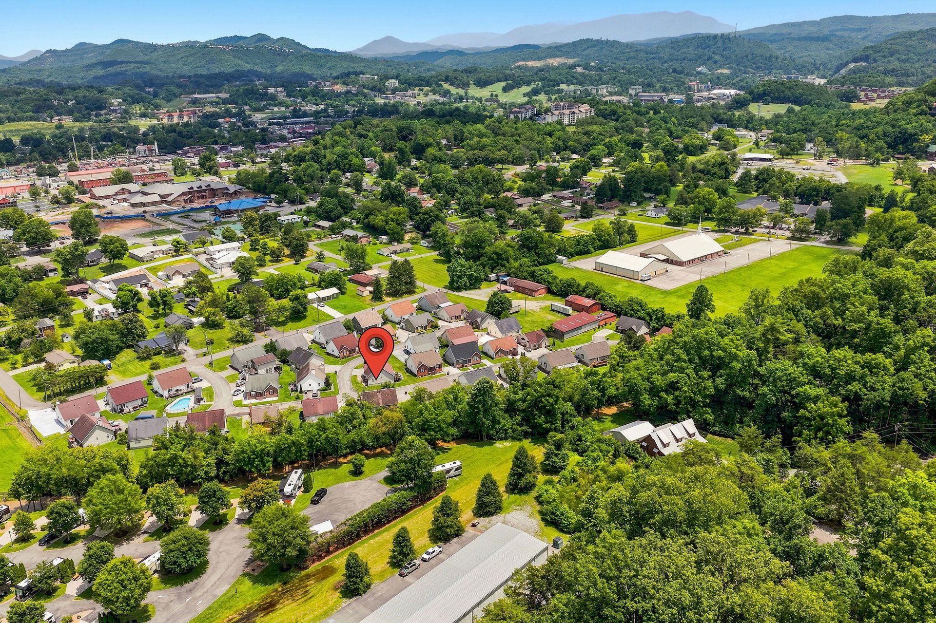 Aerial perspective showcasing the propertys setting within a lush, green neighborhood surrounded by mountains and natural landscapes—a peaceful area for travelers to explore.