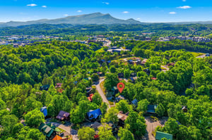 Aerial view showcasing the propertys location within a scenic mountain community, surrounded by lush forests and rolling peaks.