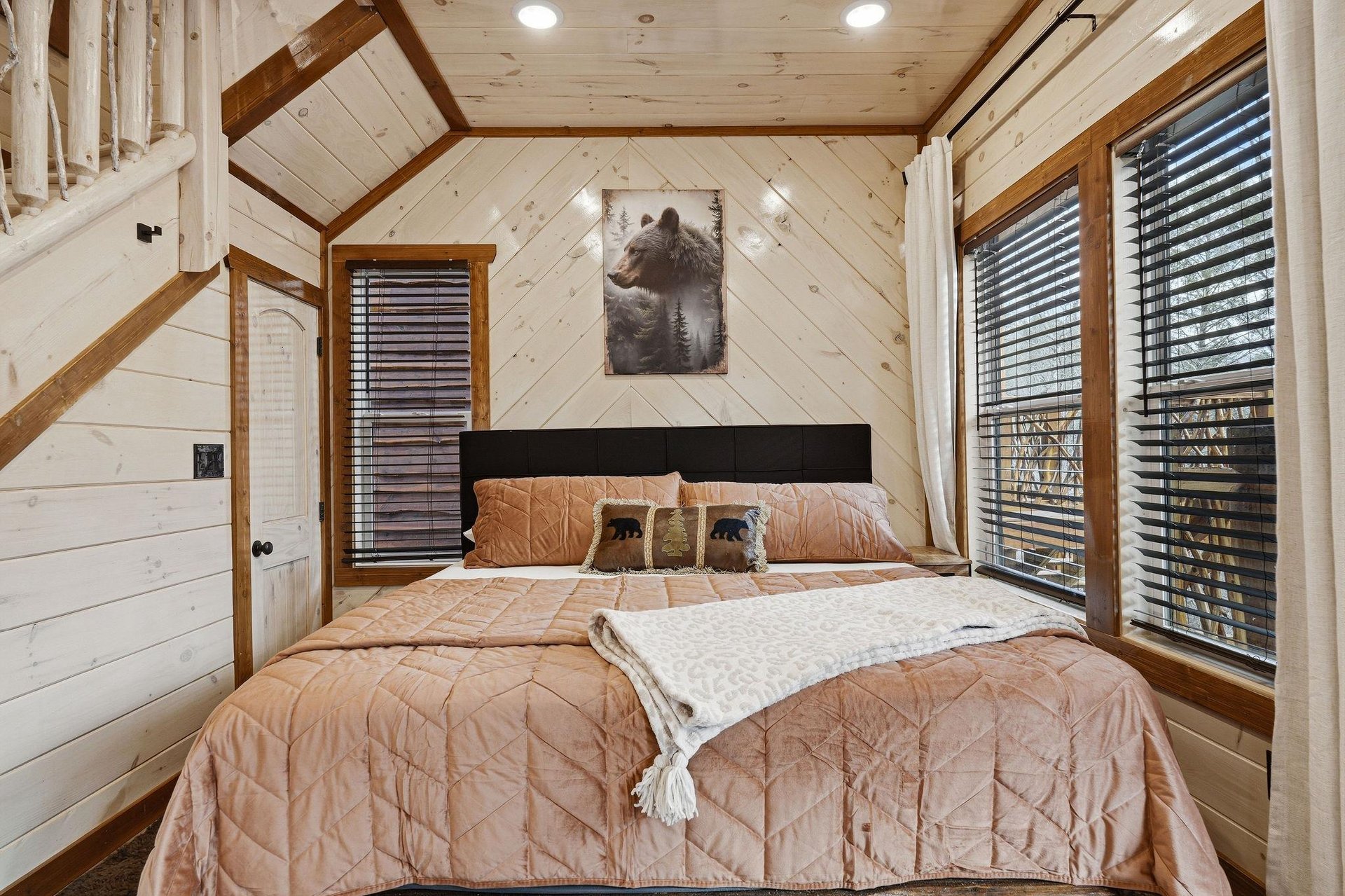 Cozy up in this charming rustic bedroom where warm wood surrounds your restful retreat beneath vaulted ceilings.