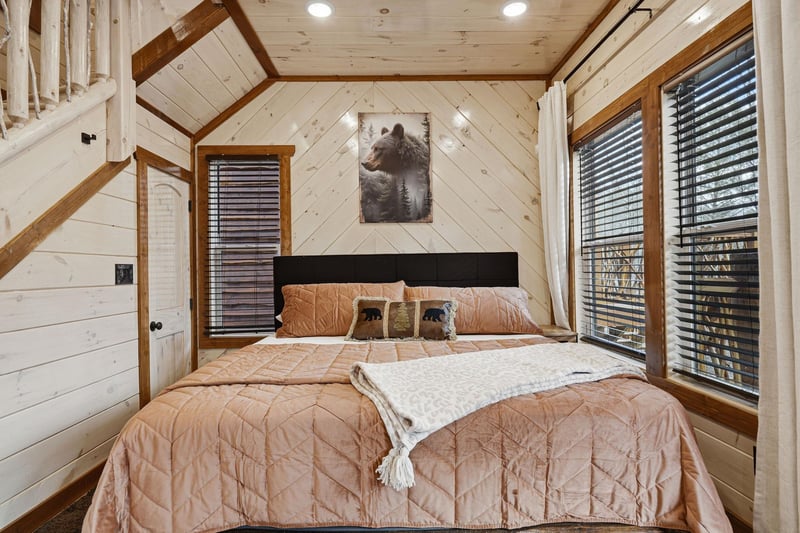 Cozy up in this charming rustic bedroom where warm wood surrounds your restful retreat beneath vaulted ceilings.