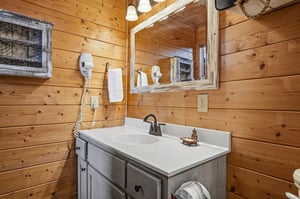 Rustic woodpaneled bathroom with modern fixtures, hair dryer, and fresh towels waiting for your arrival.