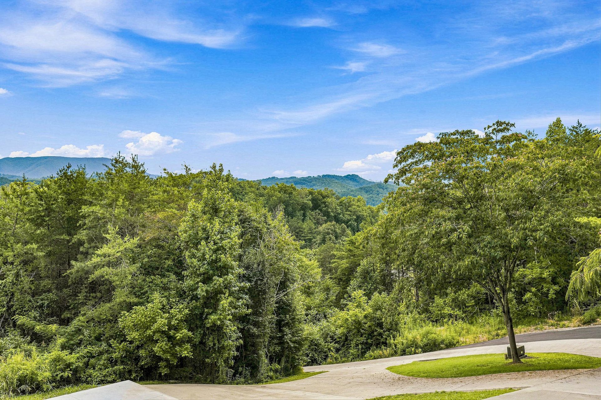 Nestled in a peaceful mountain setting surrounded by lush forests and scenic views visible from the propertys arrival area.
